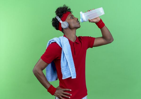 观点站在侧视图年轻的运动男子戴头带运动头带饮用水