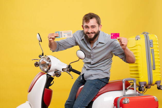 旅游旅游概念与年轻自信的胡须男子坐在摩托车上持有银行卡和黄色的车票车辆摩托车银行