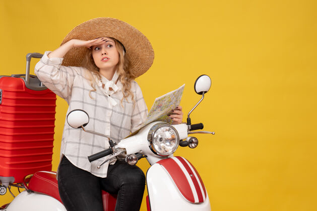 帽子头戴帽子坐在摩托车上拿着地图的年轻女子的俯视图集中在黄色的东西上抱摩托车玩
