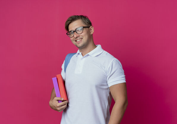 粉色笑容可掬的年轻帅气男生背着书包拿着粉红色的书学生年轻包