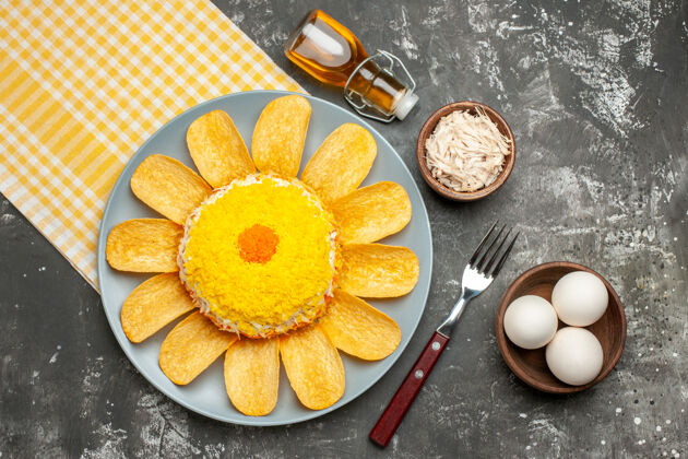 饭沙拉的俯视图在左边 黄色的餐巾在下面 奶酪叉油瓶和一碗鸡蛋放在深灰色的桌子上左边瓶子食物