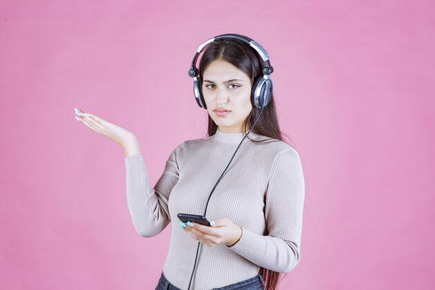 工人戴着耳机的年轻女子不喜欢播放列表中的音乐年轻消极轨道