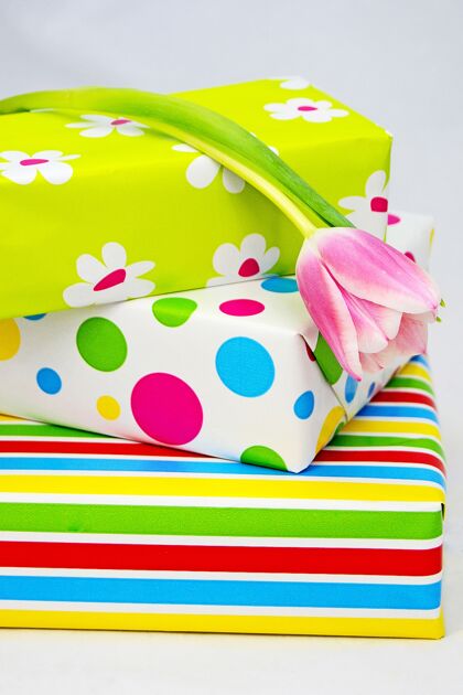 纸特写镜头的包装彩色礼品盒和郁金香上的白色表面红色生日配件