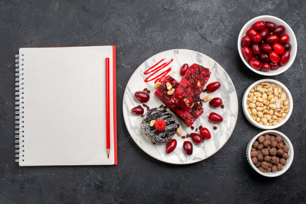石榴在灰色的桌子上俯瞰美味的坚果和山茱萸蛋糕片午餐餐糖