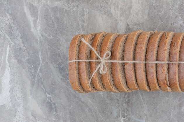 健康用绳子把棕色面包片放在大理石表面面包整个谷物