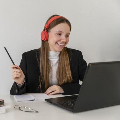耳机中镜头笑脸女人用笔记本电脑工人工作事业