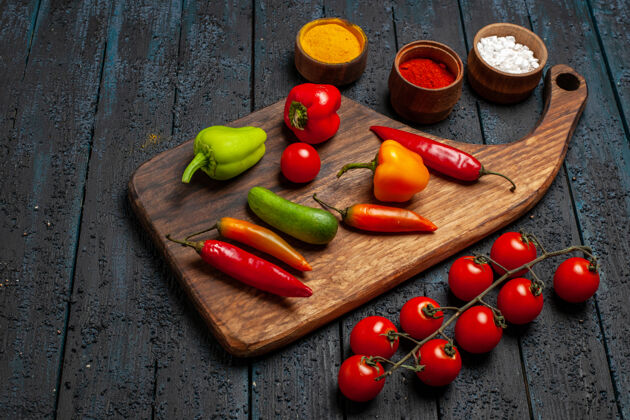 胡椒在黑暗的桌子上看到不同的辣椒和调味品西红柿桌子前面