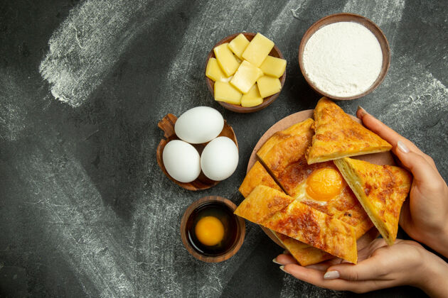 糕点顶视图烤鸡蛋面包与新鲜鸡蛋和切片奶酪在灰色的办公桌上果仁水果烘焙