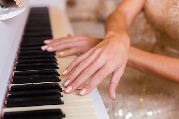 昂贵穿着金色圣诞晚礼服在家弹钢琴的女人姿势时尚优雅
