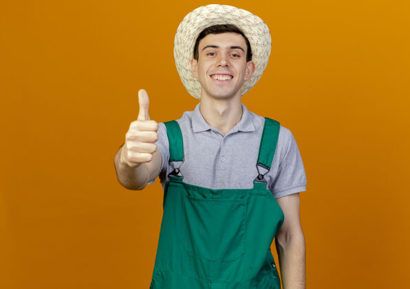 橙色微笑的年轻男园丁戴着园艺帽竖起大拇指拇指男性复制