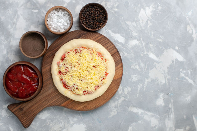 丰富多彩在浅白的桌子上俯瞰生比萨饼 上面有奶酪和不同的调味品美味配料新鲜