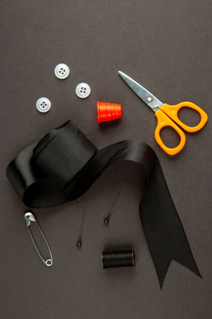 针织顶视图黑色蝴蝶结与剪刀和按钮在黑暗的背景缝纫顶部纽扣