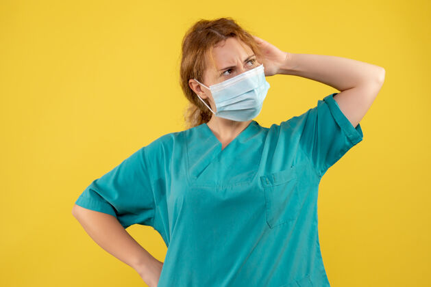 可爱黄色墙壁上戴着无菌防护面具的女医生的正视图人防护医院