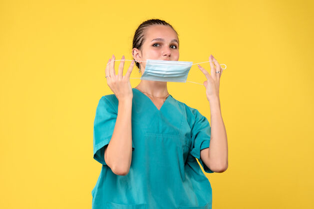 护士黄墙上穿着医疗服 戴着无菌口罩的女医生的正面图医疗健康脸