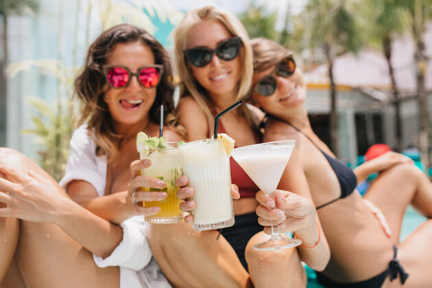鸡尾酒戴着粉色太阳镜的黑发女人在夏日休息时和朋友们欢庆着什么漂亮的棕褐色女人喝着鸡尾酒 享受着假期人黑发配件