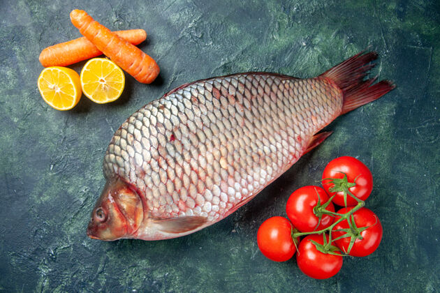 食物顶视图新鲜的生鱼肉和西红柿在深蓝色的背景海鲜番茄餐