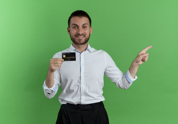 侧板笑容可掬的帅哥拿着信用卡指着隔离在绿墙上的一侧微笑男人成人