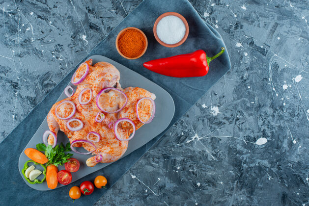 洋葱生的腌鸡肉和蔬菜放在一块布上 蓝色背景新鲜的胡椒美味的