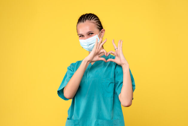 可爱黄墙上穿着医疗服 戴着无菌口罩的女医生的正面图医院病毒西装