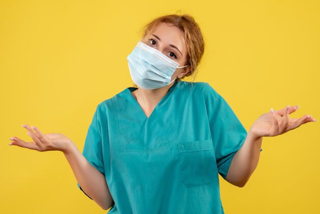 护士黄色墙壁上戴着无菌防护面具的女医生的正视图成人药健康