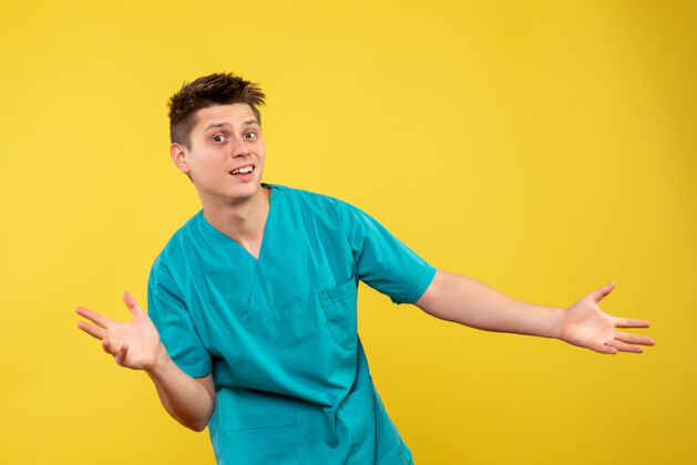 病毒黄色墙壁上穿着医疗服的男医生的正视图前面球男人