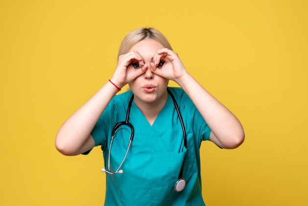 医学黄色墙壁上穿着带听诊器的医用衬衫的女医生的正视图女医生疾病美女