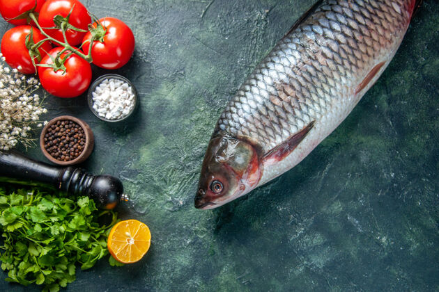 食物顶视图新鲜生鱼与绿色和西红柿在黑暗的背景顶部鲈鱼海鲜