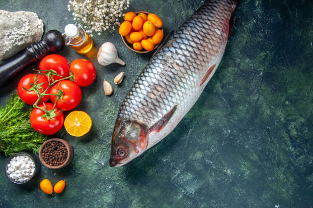 海鲜顶视图新鲜的生鱼肉与金橘和西红柿在黑暗的背景深色饮食鱼