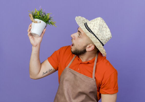 男性惊讶的男园丁戴着园艺帽 拿着花盆看空间紫色穿