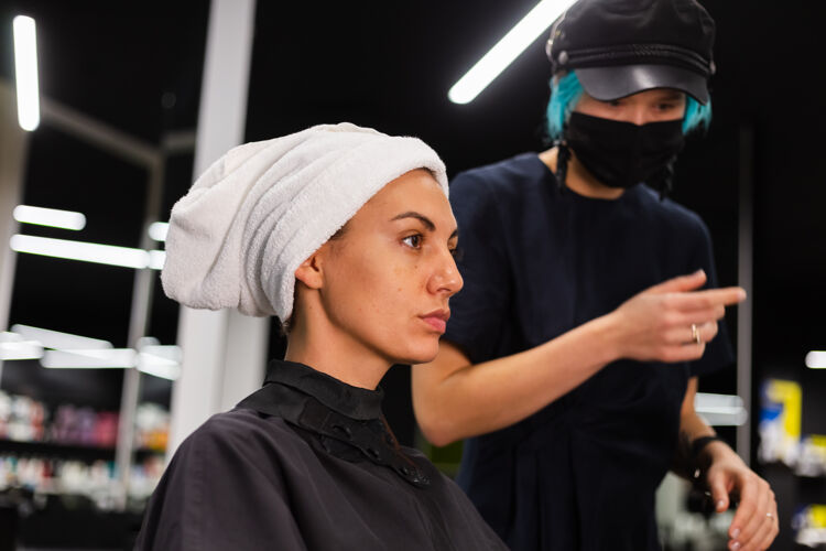 客户一个专业的女理发师给客户理发这个女孩戴着面具坐在美容院里面膜爆发工人