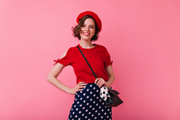 法国自信的法国女士摆出真诚的微笑浪漫的高加索妇女戴着红色贝雷帽表达积极的情绪年轻表情模特