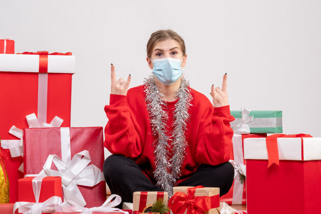 健康正面图：年轻女性戴着无菌面具坐着 手里拿着圣诞礼物礼物年轻女性绝育