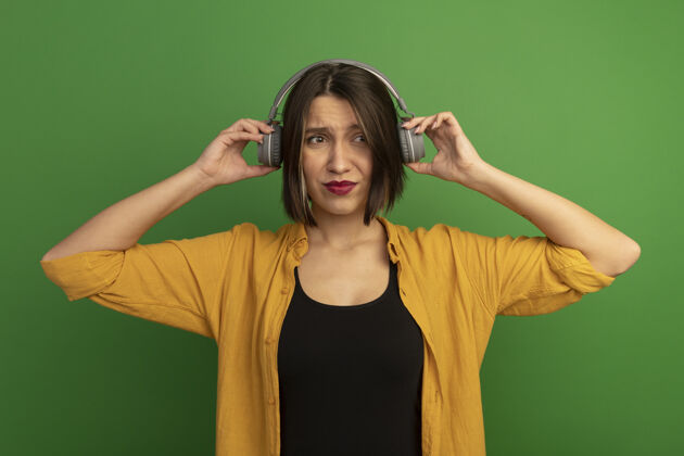 女人戴着耳机的漂亮白种女人站在绿色的一边看时尚漂亮黑发