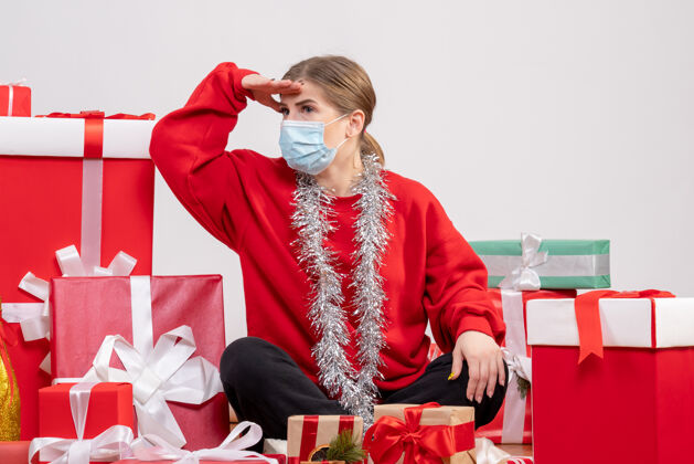 礼物正面图：年轻女性戴着无菌面具坐着 手里拿着圣诞礼物年份桌子圣诞节