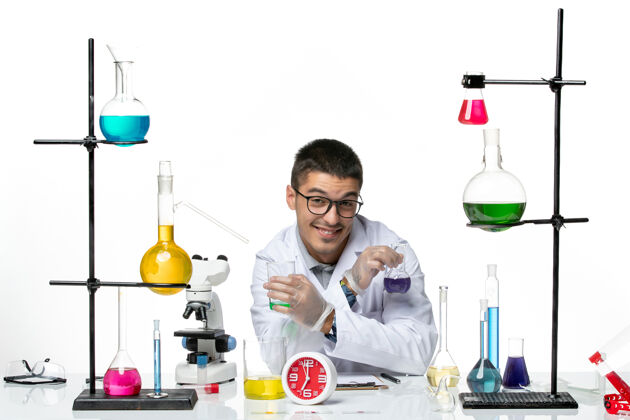 玻璃正面图：身穿白色医疗服的男性化学家拿着装有溶液的烧瓶 在白色背景上微笑着病毒科学冠状病毒-大流行实验室套装实验室烧杯