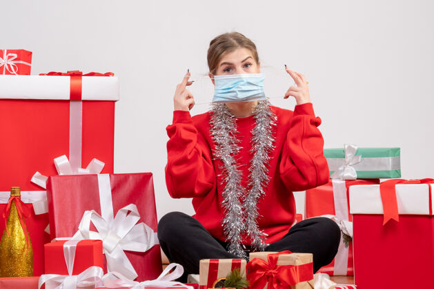 礼物正面图：年轻女性戴着无菌面具围坐在圣诞礼物旁礼物快乐围着