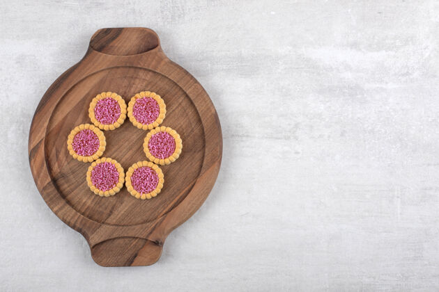 小点心石头桌上放着一盘粉红色的甜饼面包房松脆小吃