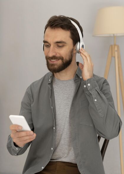 男人戴着耳机在手机上听音乐的人像男人科技设备