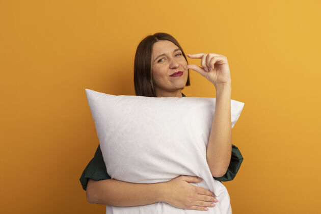 年轻可爱的白种女人抱着枕头 假装拿着桔子上的东西姿势女人时尚