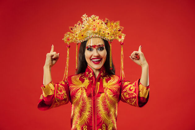 中国中国传统的优雅女子在红色背景的工作室里传统微笑女孩