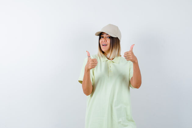 魅力穿着t恤 戴着帽子 向上竖起大拇指的年轻女士 看上去很积极正面视图漂亮护理帽子