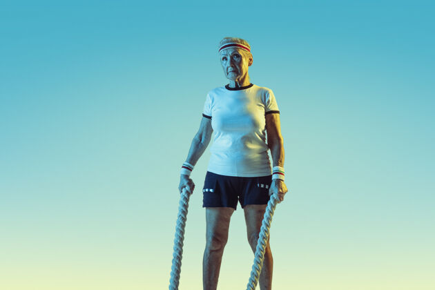 健康高级女子运动装训练与绳索梯度背景 霓虹灯表情发球动作