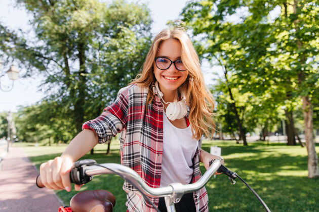 道路一头金发的快乐女孩早上骑在公园里一张迷人的年轻女士骑着自行车表达积极情绪的户外照片女性城市微笑
