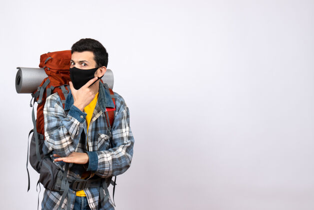 视图正面图：背着背包 戴着面具 手放在下巴上的男性旅行者男性成人人