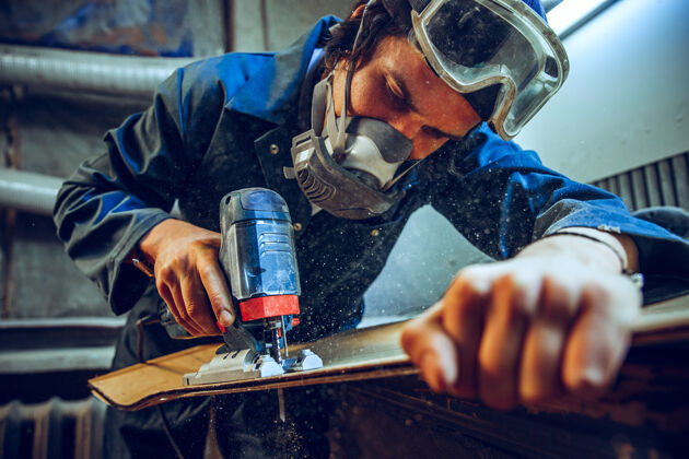 工匠使用圆锯切割木板的木匠男工人或手持电动工具的手巧工人的施工详图木材圆形工作