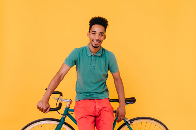 放松自信的男性自行车手摆出黄色的姿势室内有胡子的非洲男子骑自行车的镜头夏天美国非洲