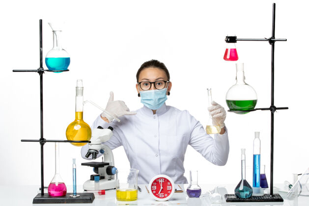 飞溅前视图：身穿白色医疗服的女化学家 带面罩 背景为浅白色 化学家实验室病毒冠状病毒飞溅化学家视图实验室