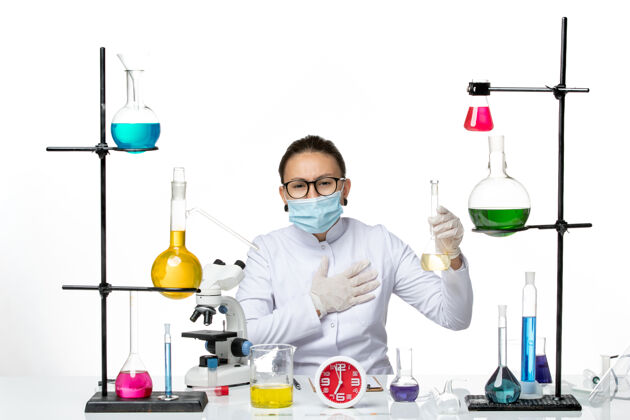 视图前视图：身穿白色医疗服的女化学家 带面罩 背景为浅白色化学家实验室病毒冠状病毒-飞溅解决方案科学实验室