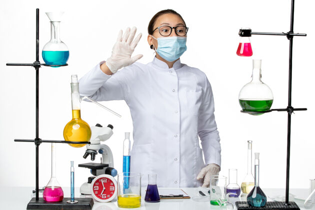 病毒前视图穿着医疗服和面具的女化学家在白色背景上向某人挥手病毒化学实验室covid-飞溅前面挥手医生
