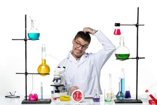 烧杯前视图穿着白色医疗服的男性化学家坐在浅白背景的病毒科学研究实验室里准备工作医学科学工作